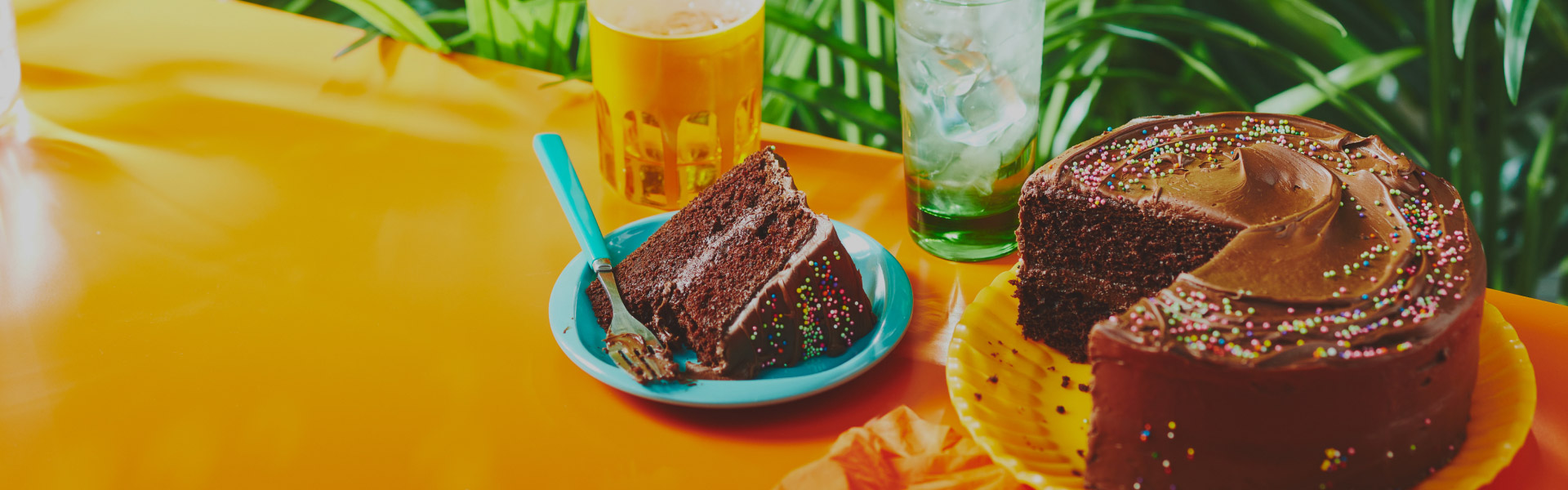 Orange tabletop with chocolate cake with slice cut out and served on blue side plate