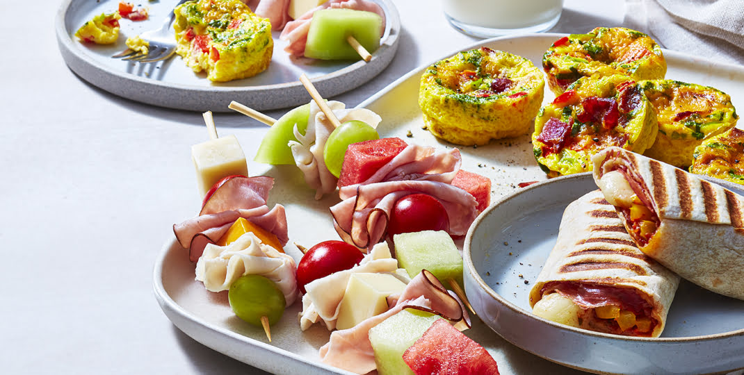 Plate of deli meat kabobs, frittatasm and pizza wrap on a white background