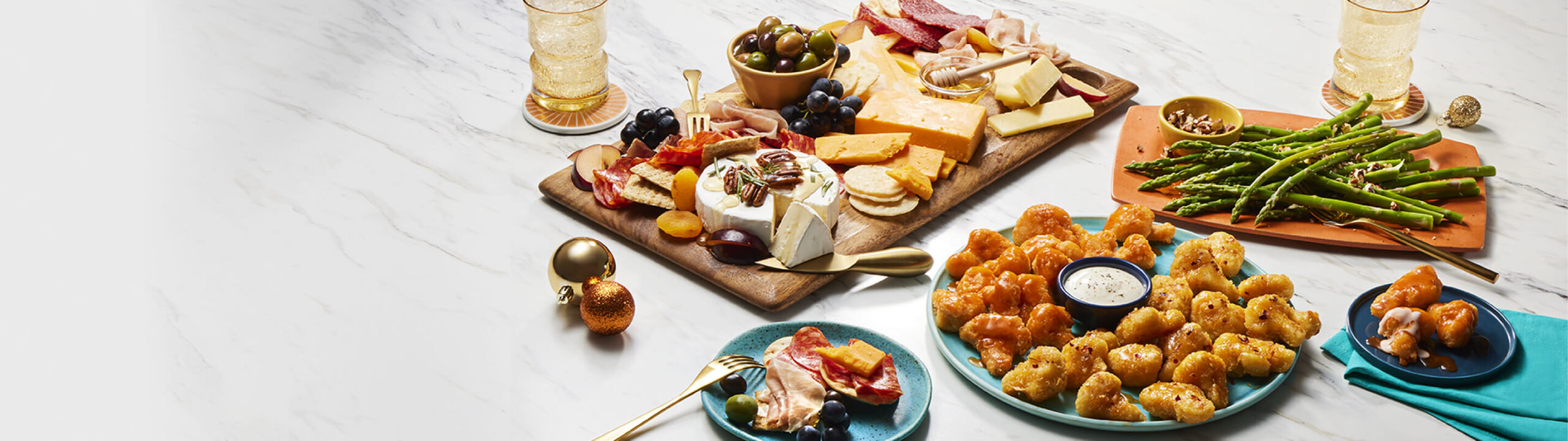 A charcuterie board, a mixed appetizer plate, nut-topped green beans, and a plate with plant-based meatballs and chickenless chicken strips.