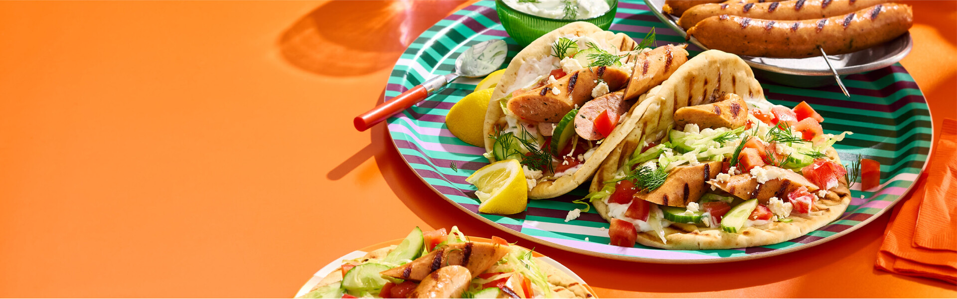 Three grilled sausage souvlaki and a skewer of grilled chicken sausage on an orange background.