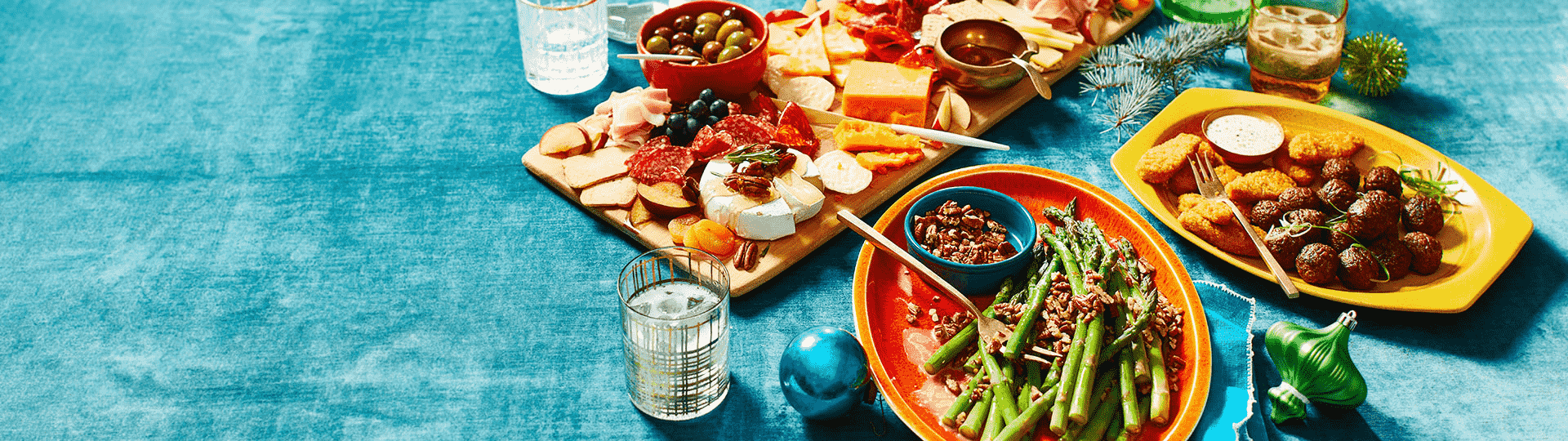 A charcuterie board, a mixed appetizer plate, nut-topped green beans, and a plate with plant-based meatballs and chickenless chicken strips.
